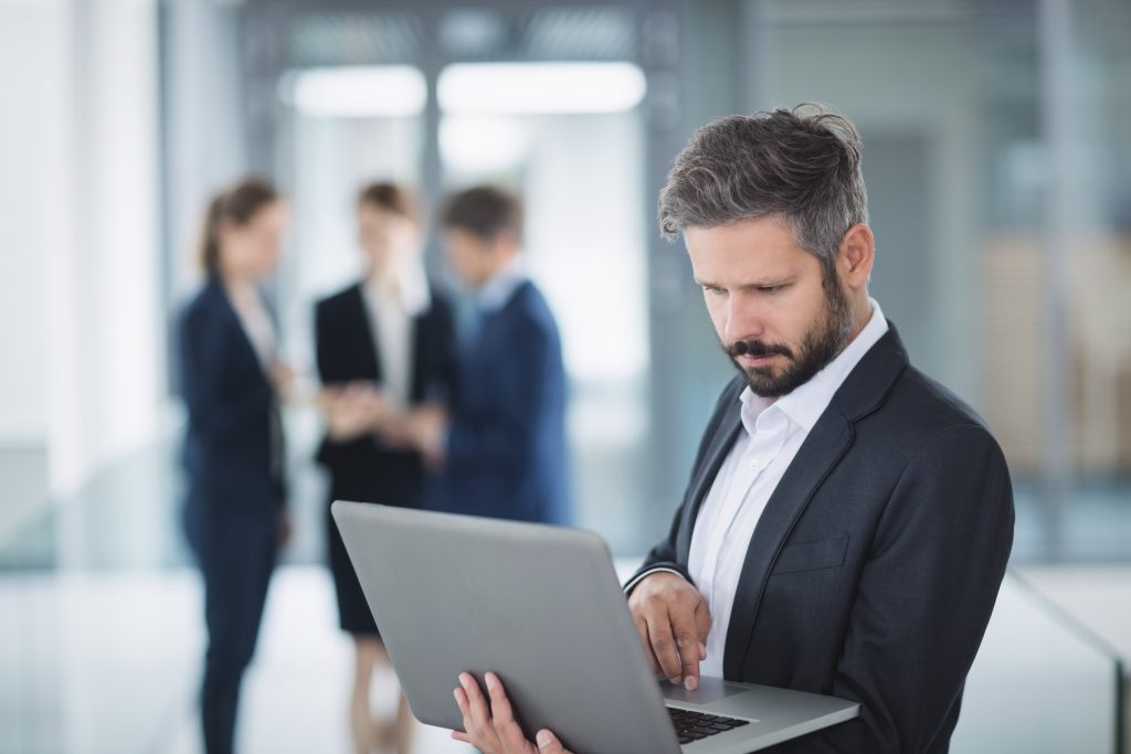 Businessman standing in office and using laptop